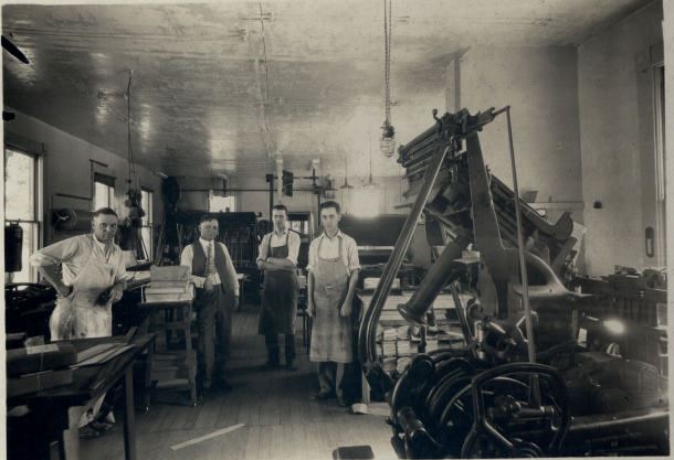 A group of people standing outside a shop taken in the 1800s.